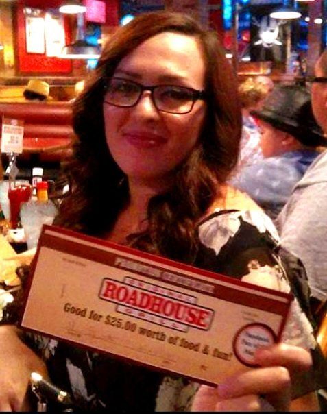 A woman is holding a roadhouse premium certificate
