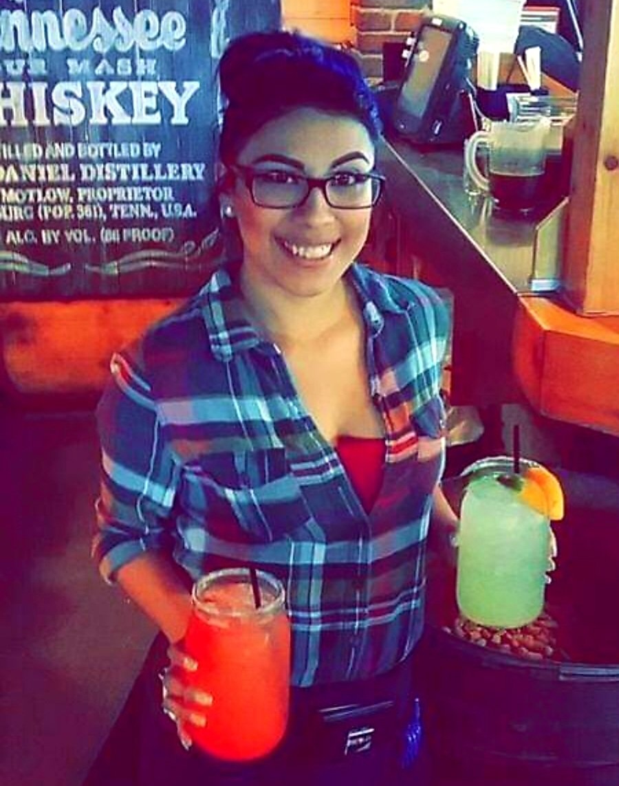 A woman holding two drinks in front of a sign that says tennessee hiskey