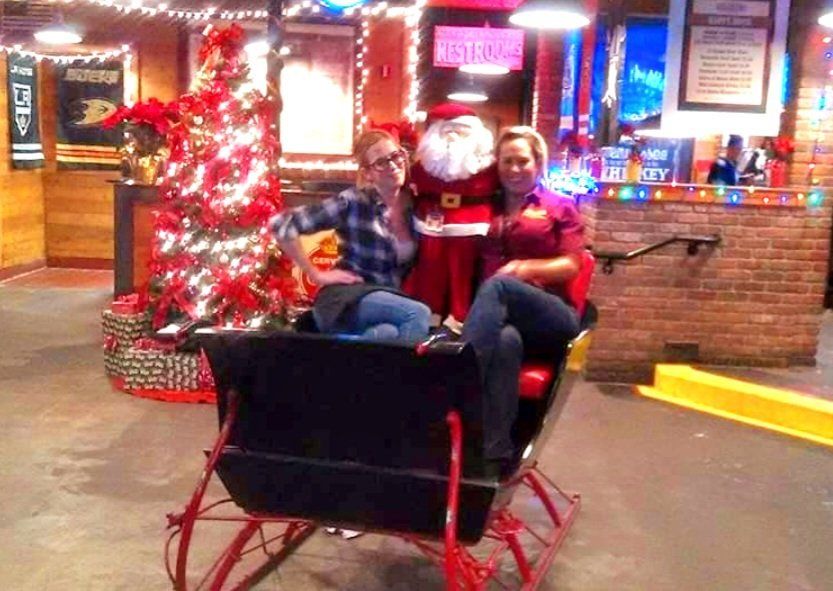 Two women are sitting in a sleigh in front of a christmas tree