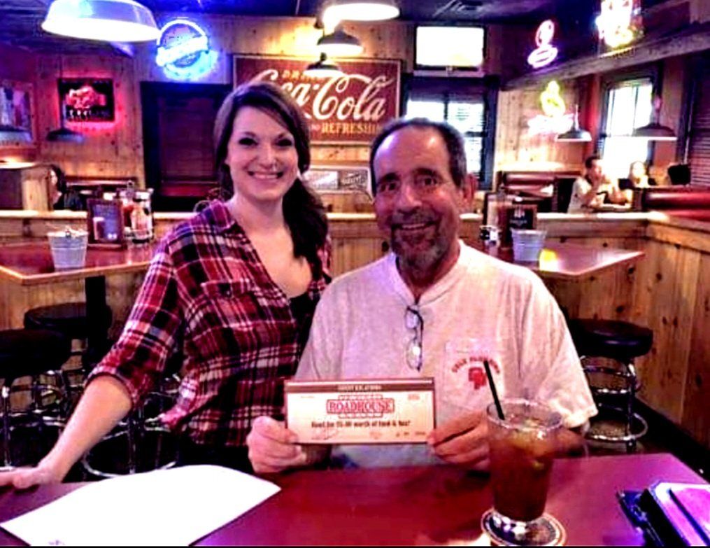 A man and a woman are sitting at a table with a coca cola sign in the background