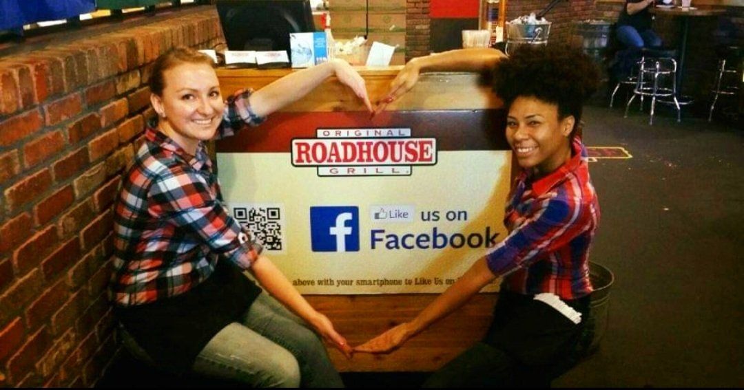 Two women are sitting in front of a sign that says roadhouse