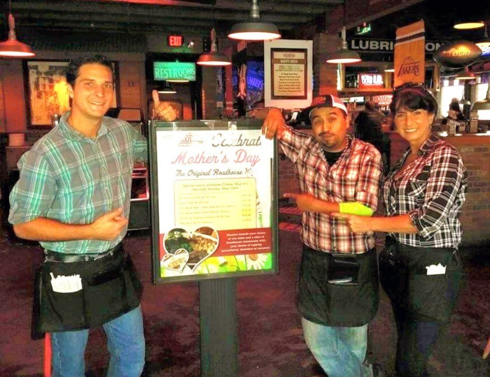 Three people standing in front of a sign that says mother 's day