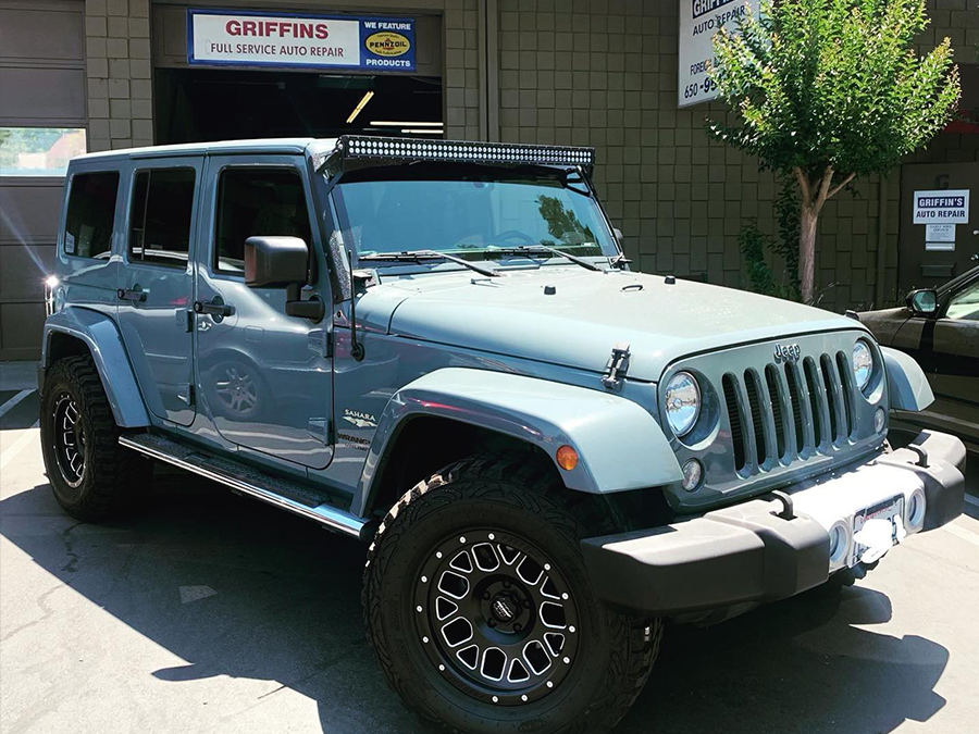 A blue jeep is parked in front of a garage that says griffins