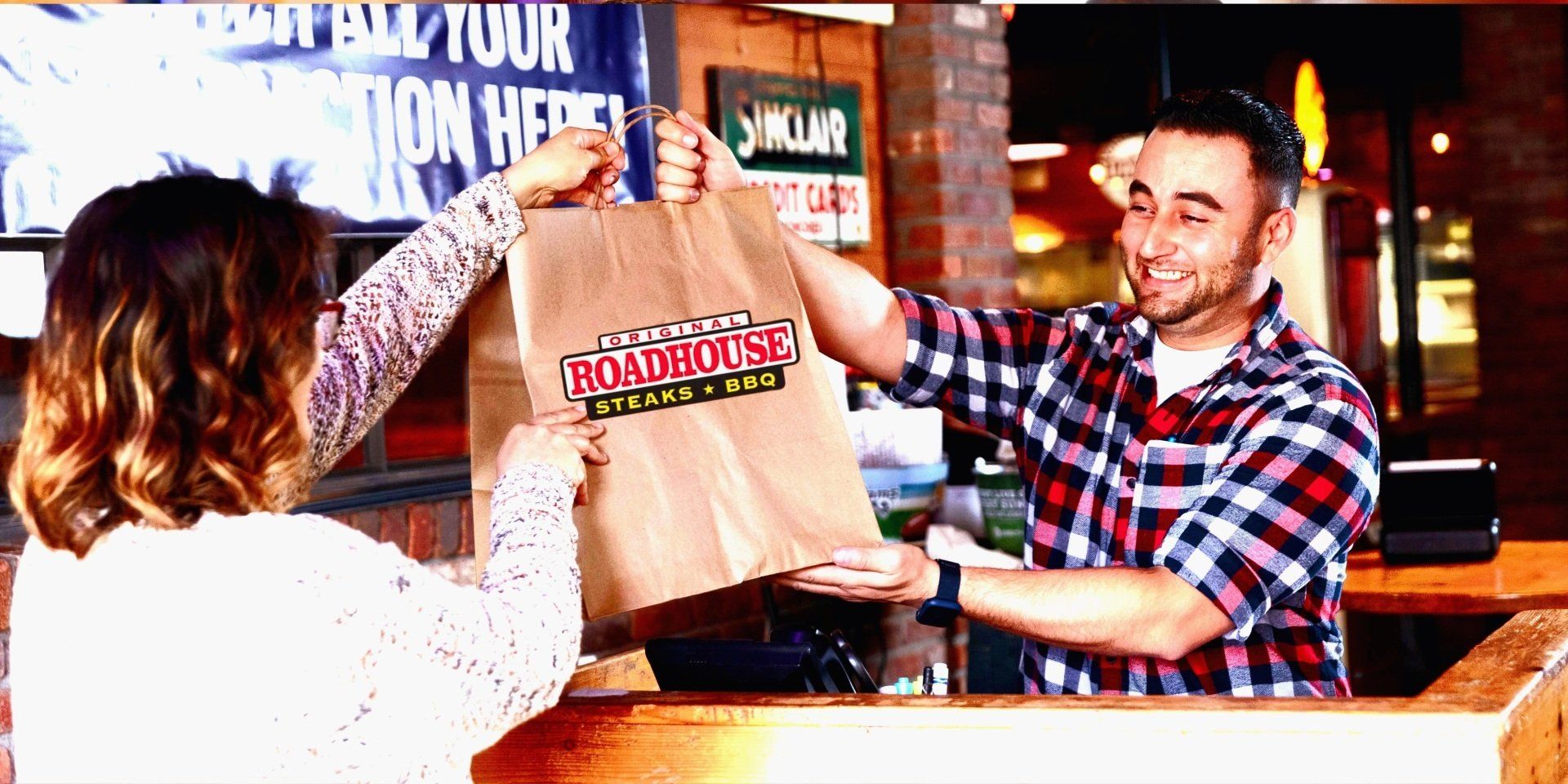 A man is giving a bag to a woman in a restaurant.