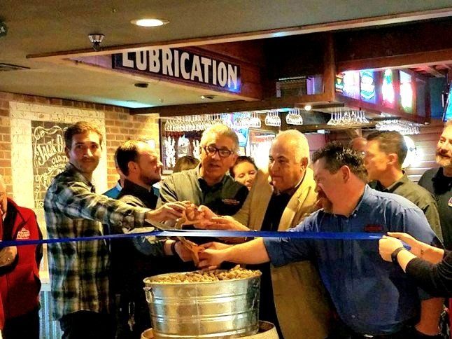 A group of men are cutting a cake under a sign that says lubrication
