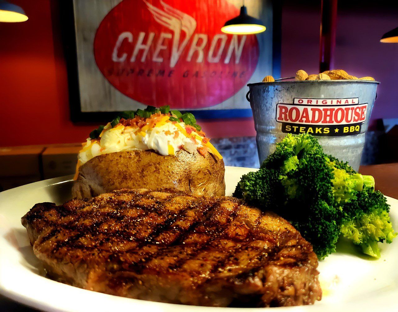 A steak with broccoli and a baked potato on a white plate