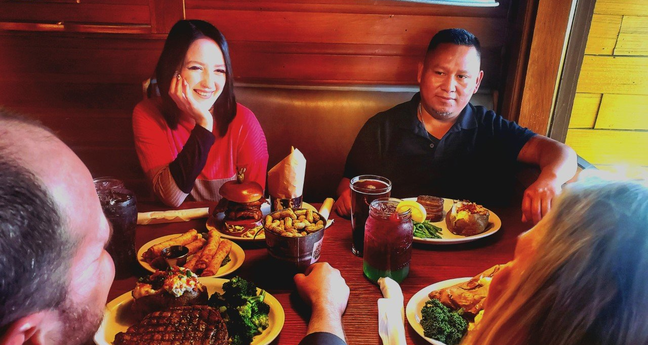 A group of people are sitting at a table with plates of food.