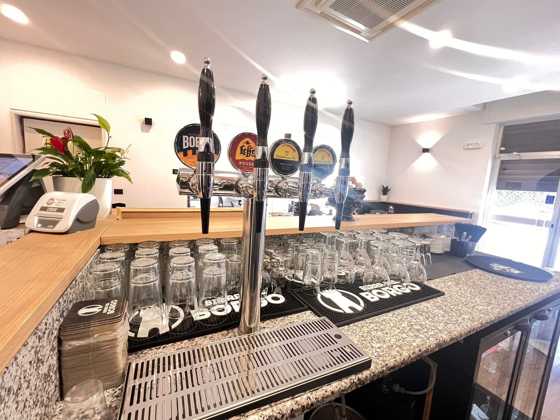 Bar con spine per la birra, bicchieri e bancone.