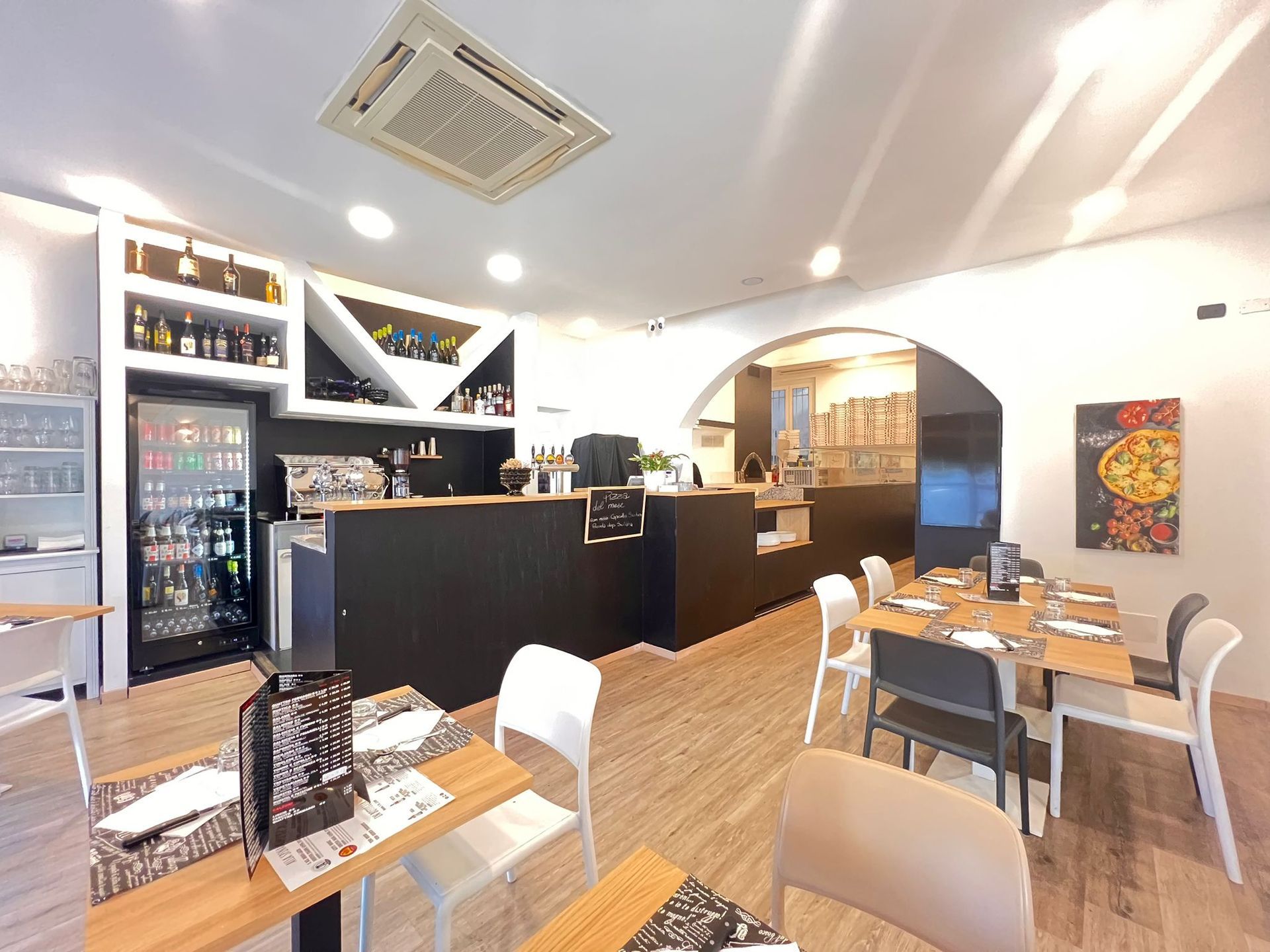 Interno di un ristorante con tavoli, un bar e un'esposizione di bevande.