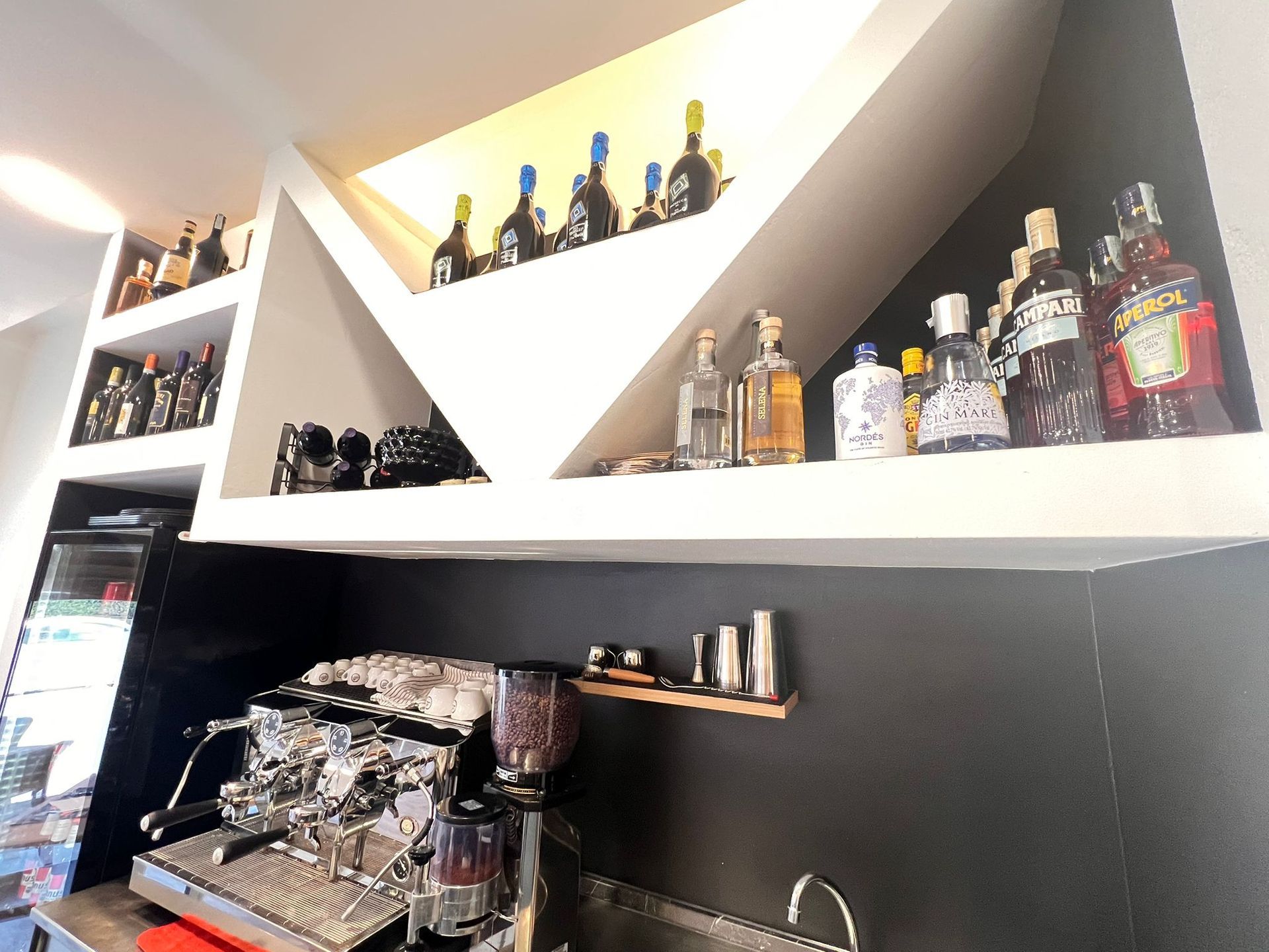 Macchina per l'espresso e bottiglie di liquore sugli scaffali di un bar.