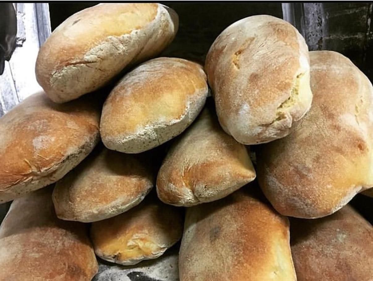 Mucchio di pagnotte rustiche dorate, probabilmente ciabatta.