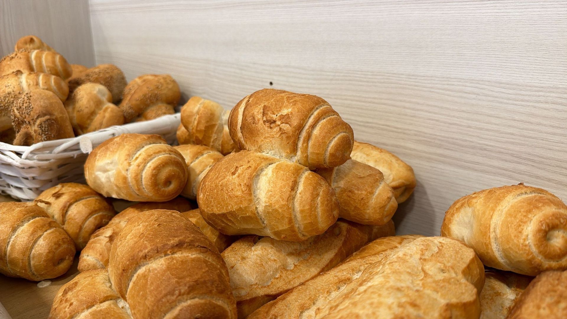 Un assortimento di panini e croissant dorati, tutti cotti al forno, ammucchiati su un bancone.