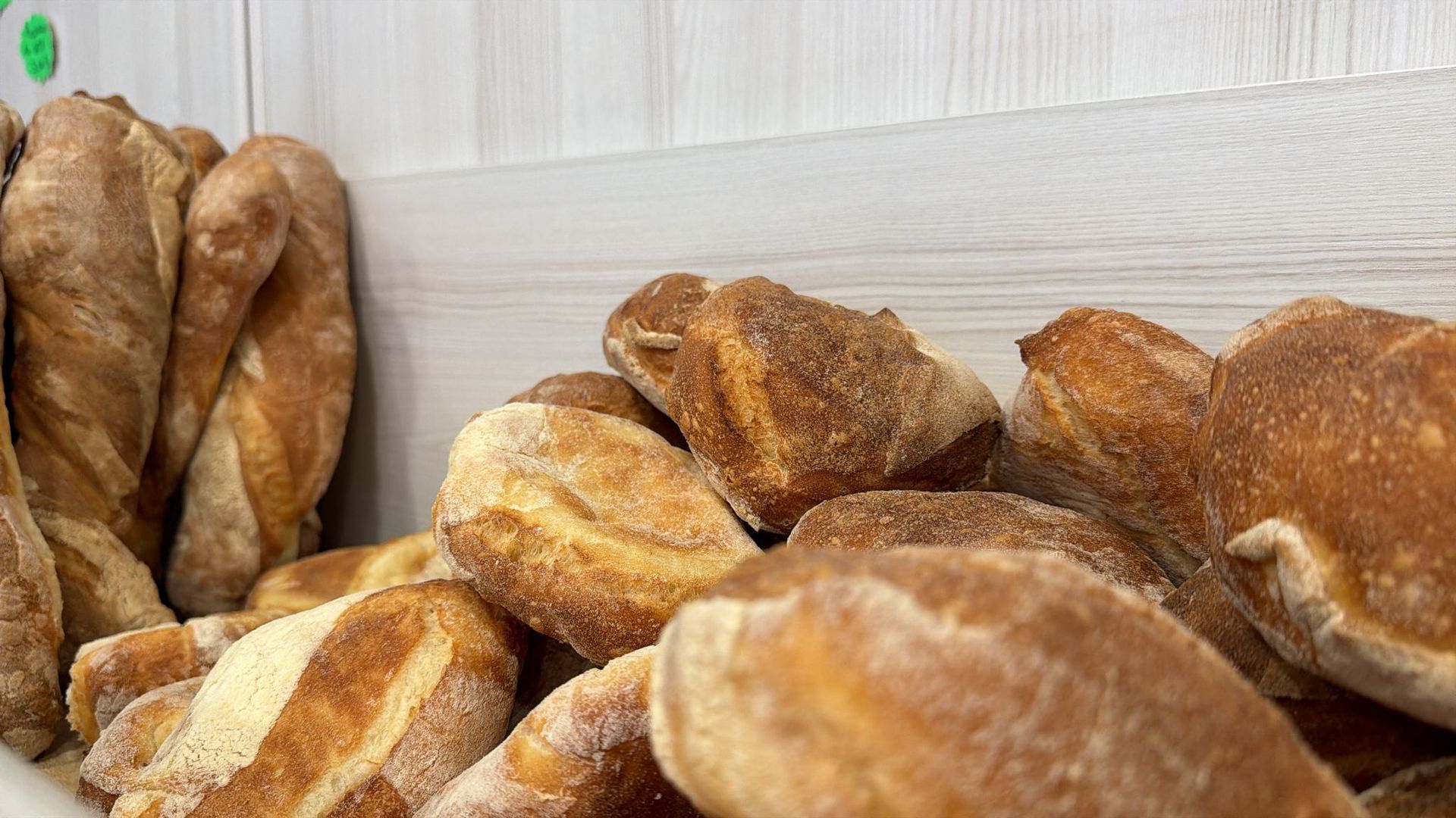 Vari tipi di pane esposti in una vetrina di panetteria, tra cui baguette e panini rustici.