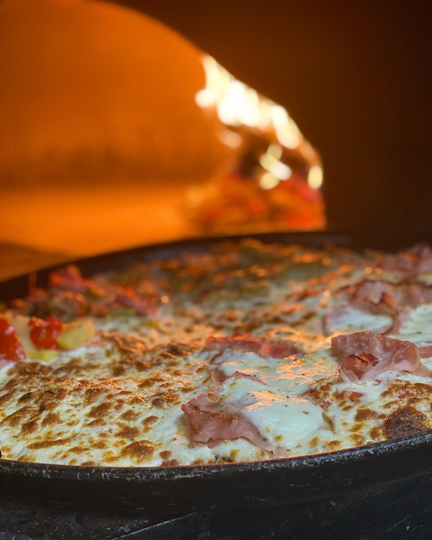 Pizza cotta in una teglia di ghisa e cotta nel forno a legna.