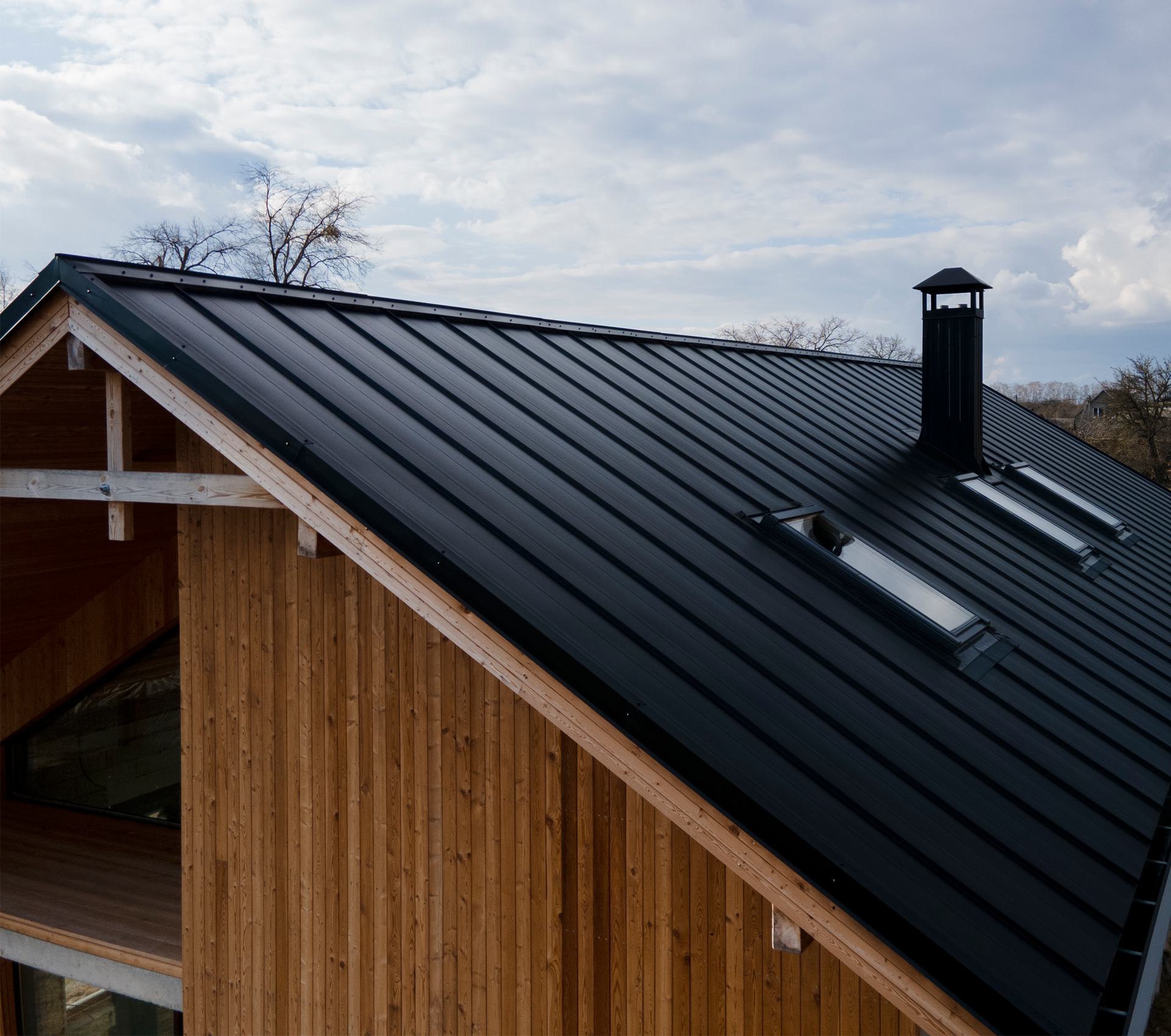 A wooden house with a black roof and skylights
