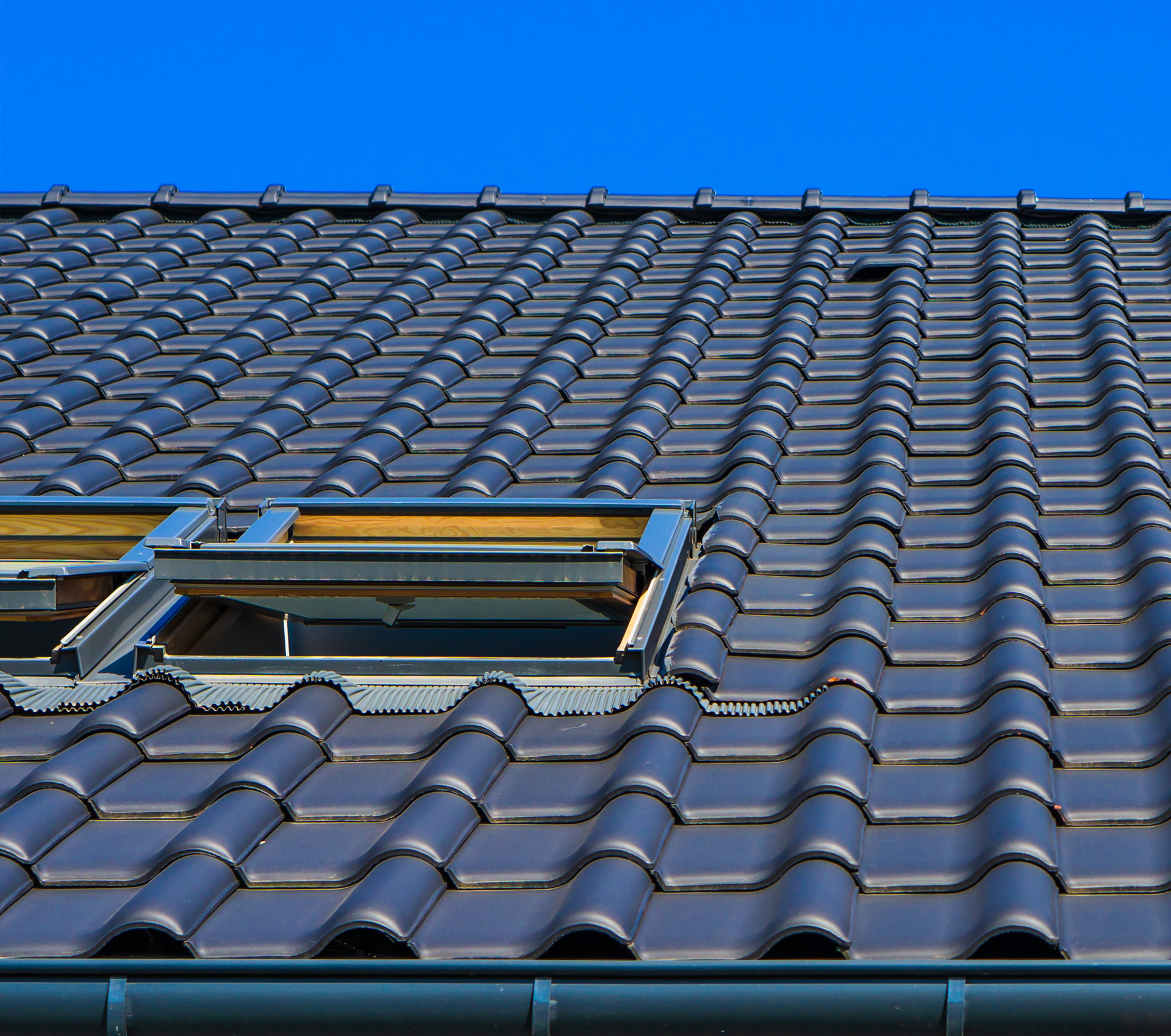 A roof with a skylight on it and a blue sky in the background.