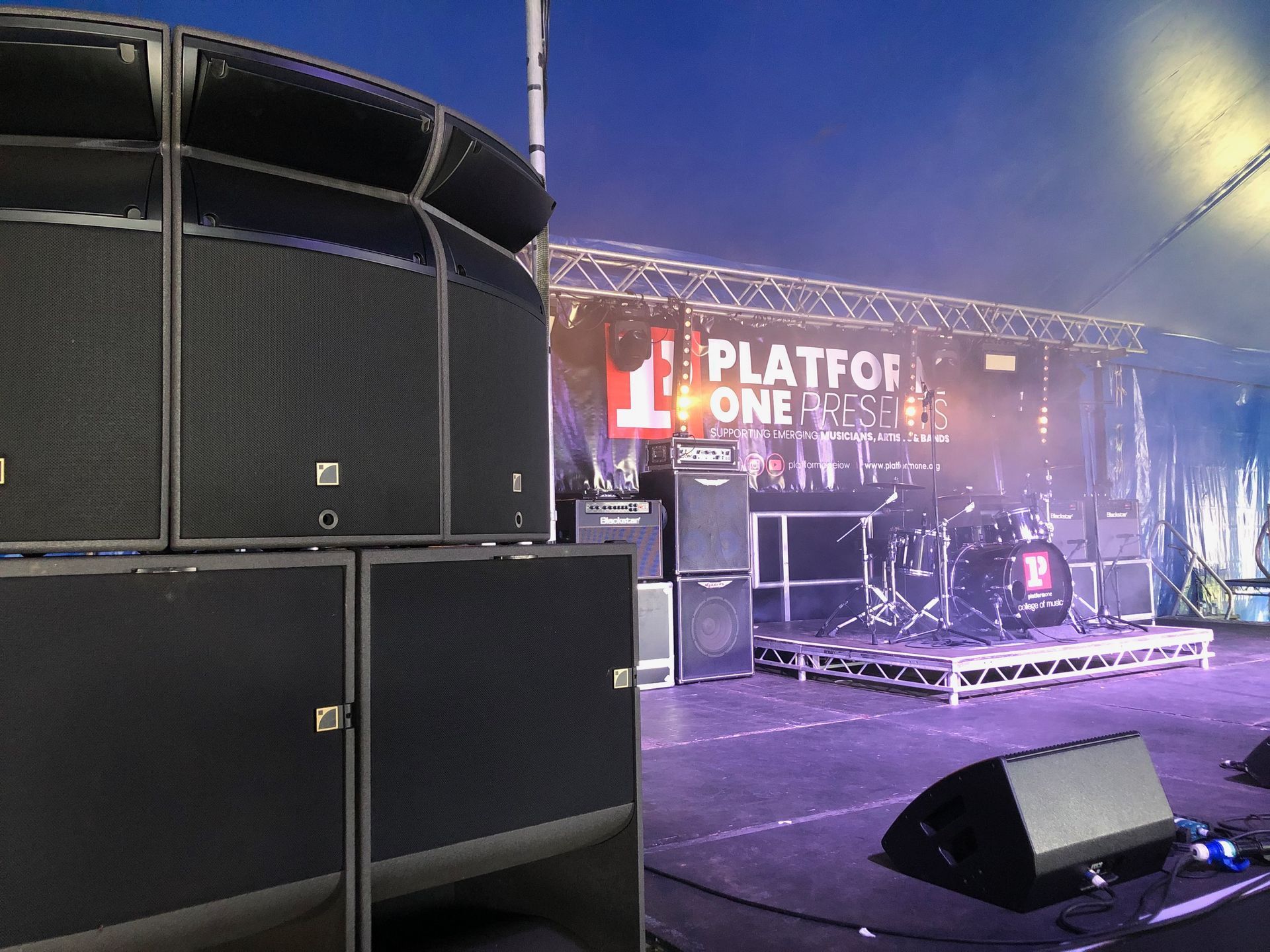 A close up of a speaker stack with a  stage with a sign that says ' Platform One' on it