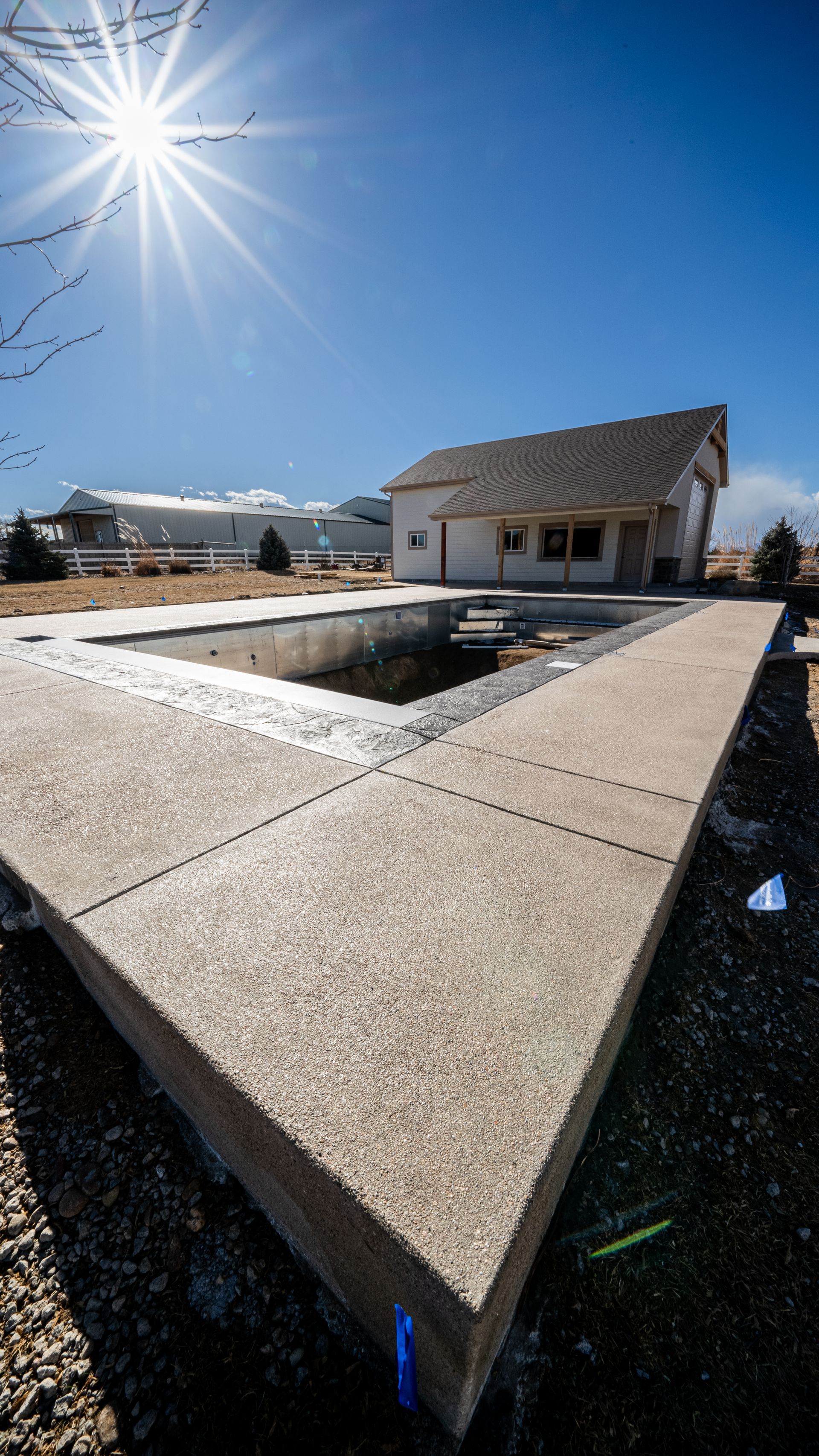Sunny backyard with a concrete geometric planter and a small house in the background