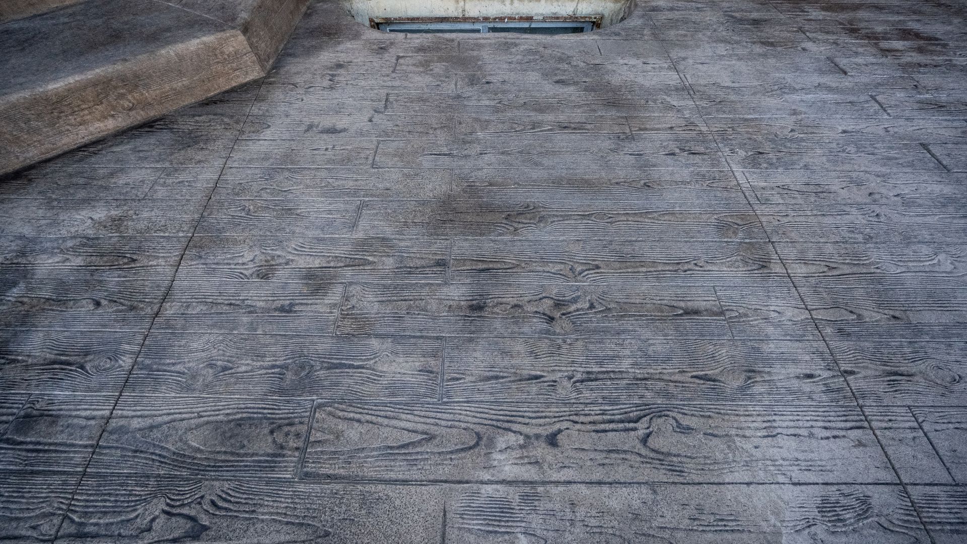 Weathered stone walkway with a textured gray surface and concrete edges