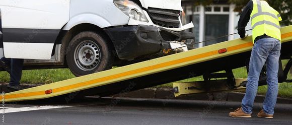 flat bed tow truck picking up a wreck