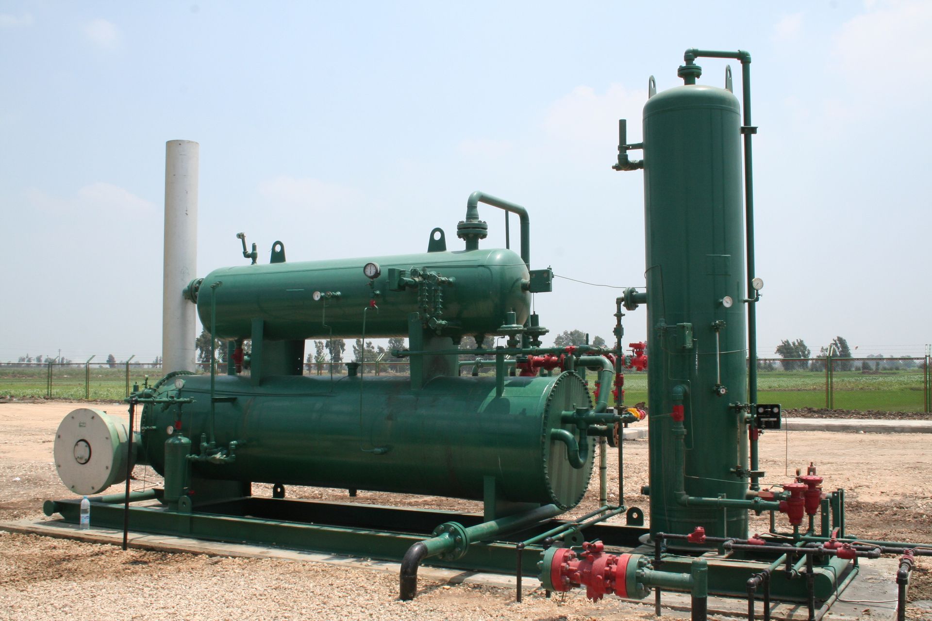A green machine is sitting on top of a dirt field.