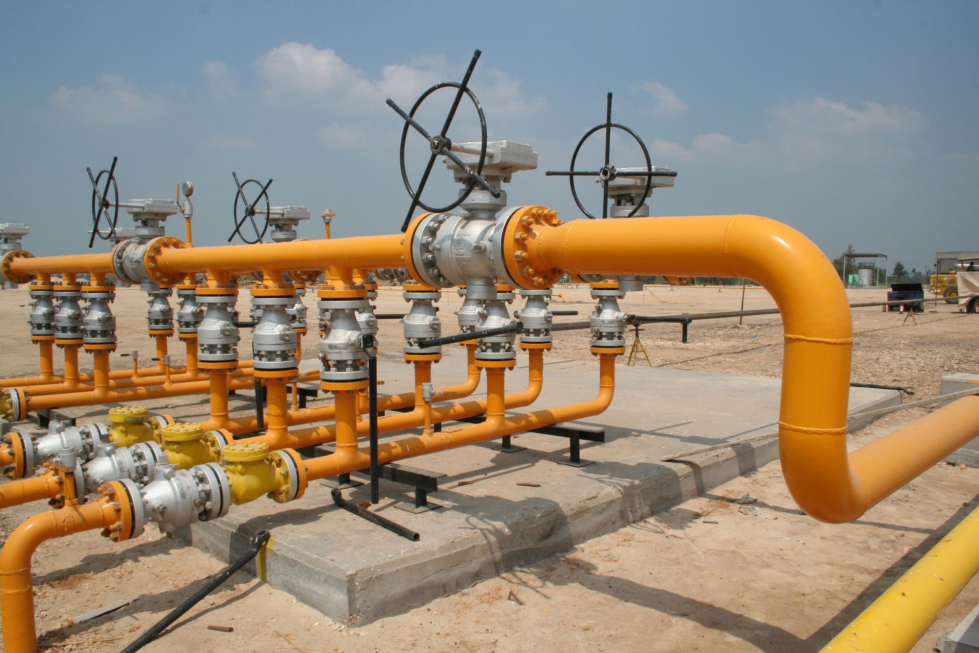A bunch of yellow pipes with a blue sky in the background