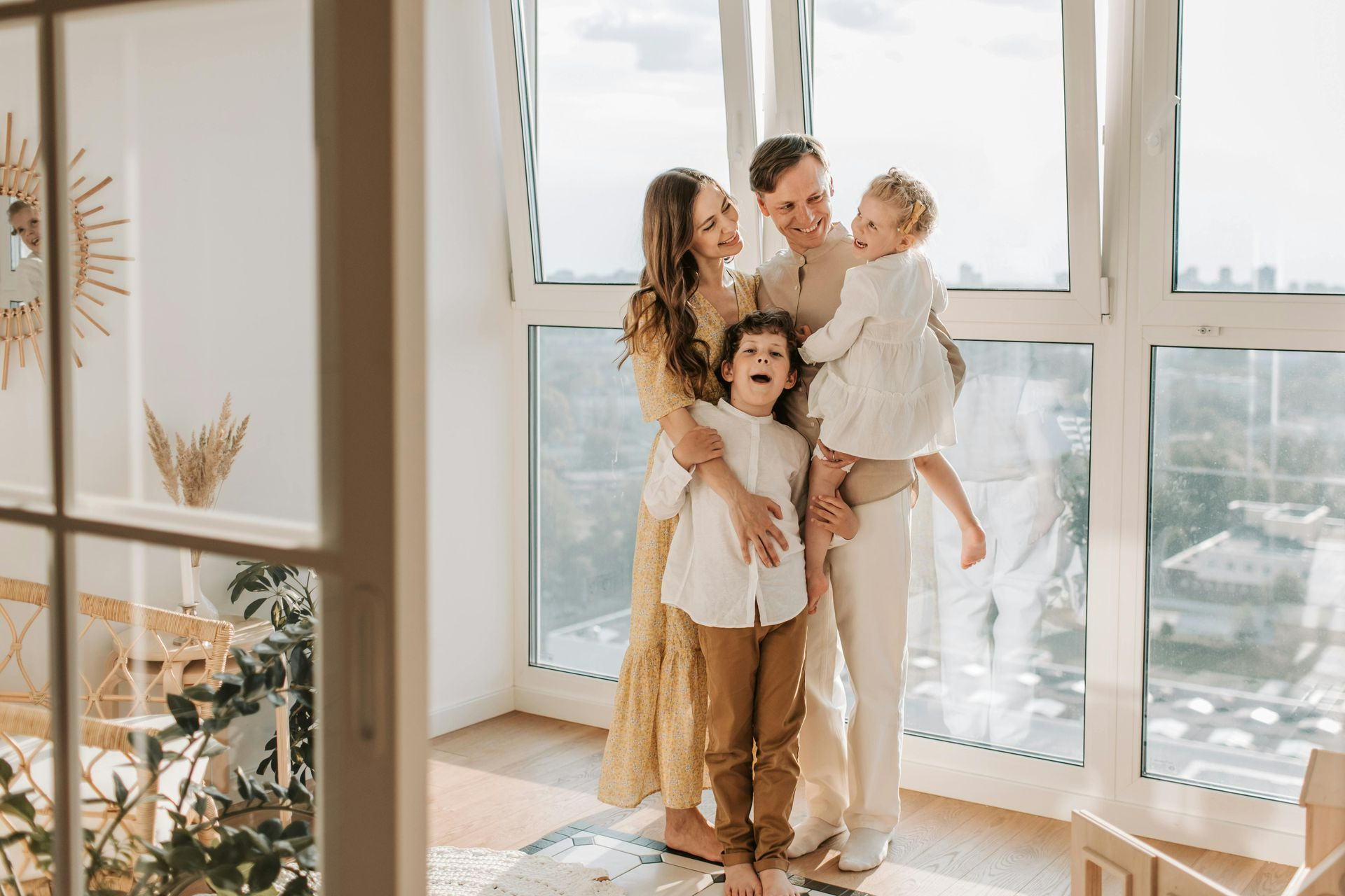 A family is standing in front of a window in a living room.