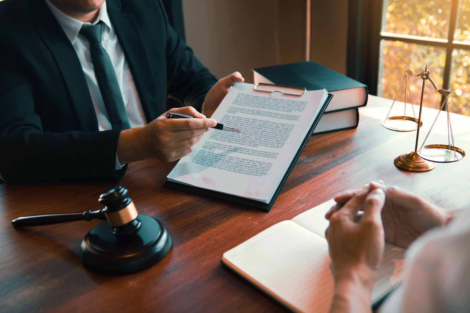 Lawyers reviewing a document at a wooden desk with a gavel, books, and scale of justice