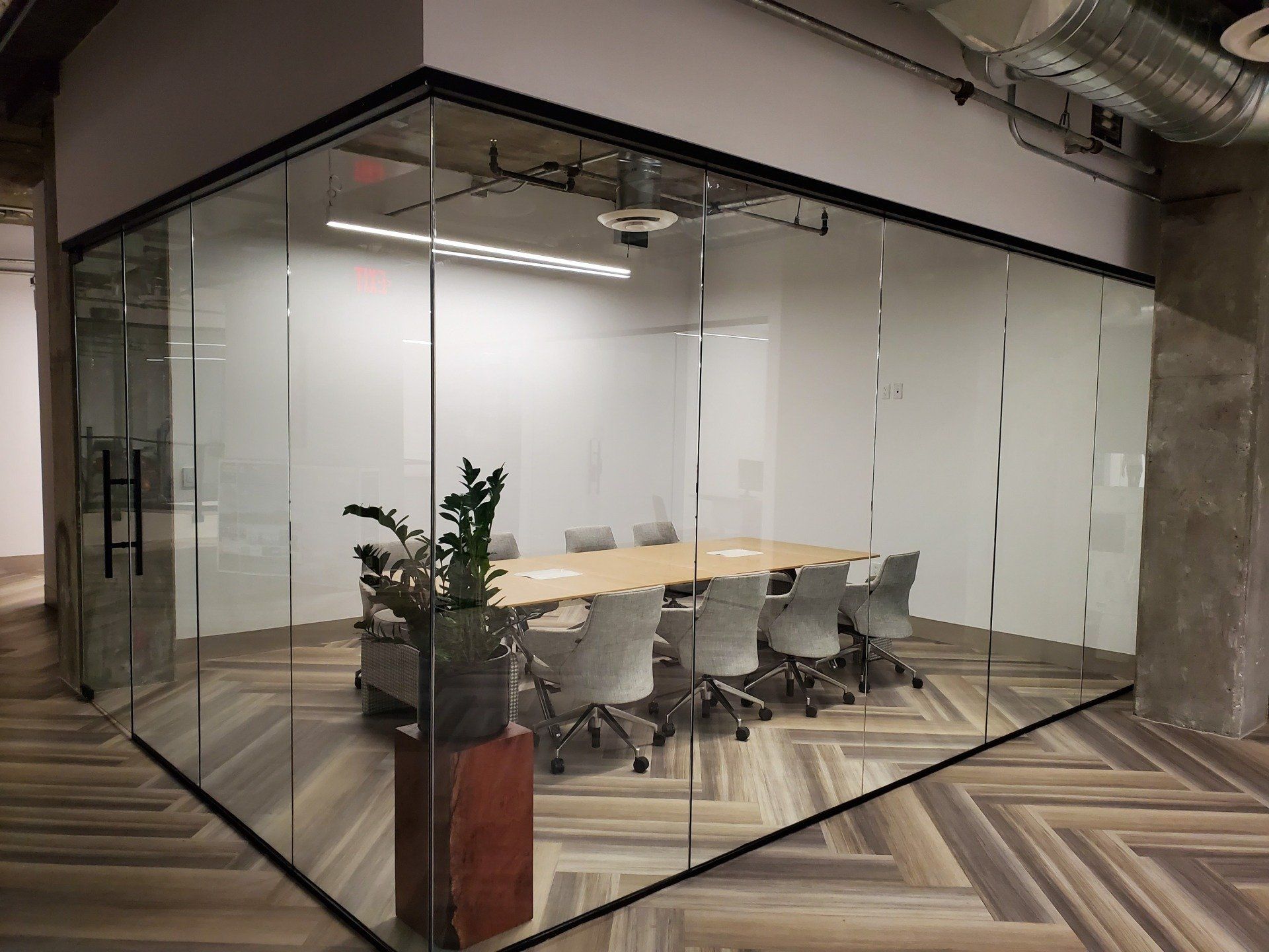 A conference room with a glass wall and a table and chairs.