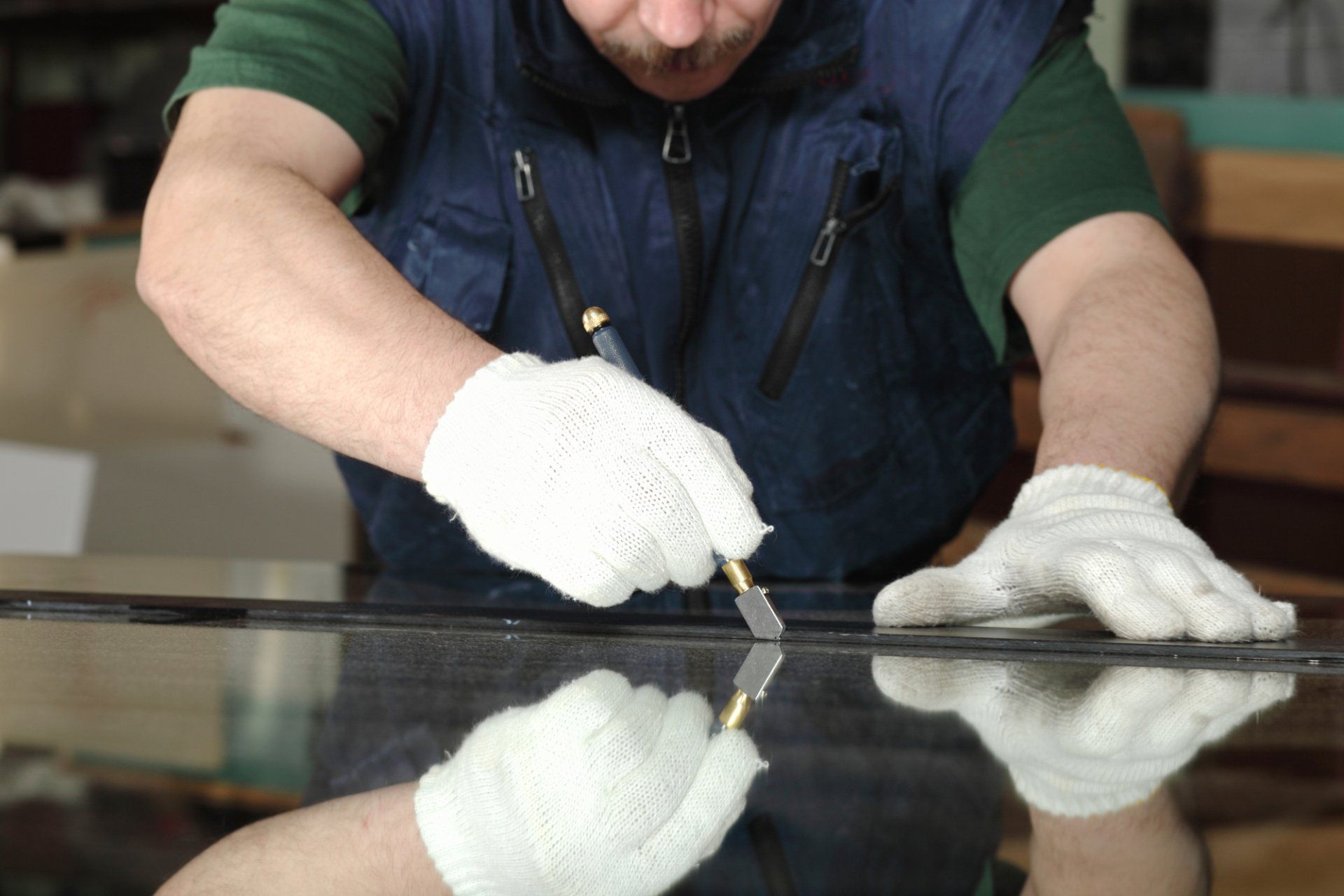 A man is cutting a piece of glass with a glass cutter.
