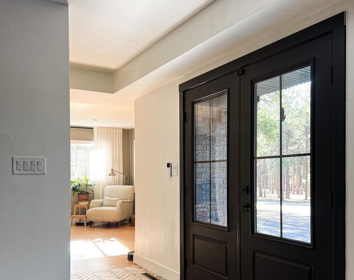 A hallway with a black door and a chair in the background.