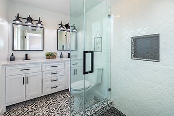 A bathroom with two sinks , a toilet , and a walk in shower.
