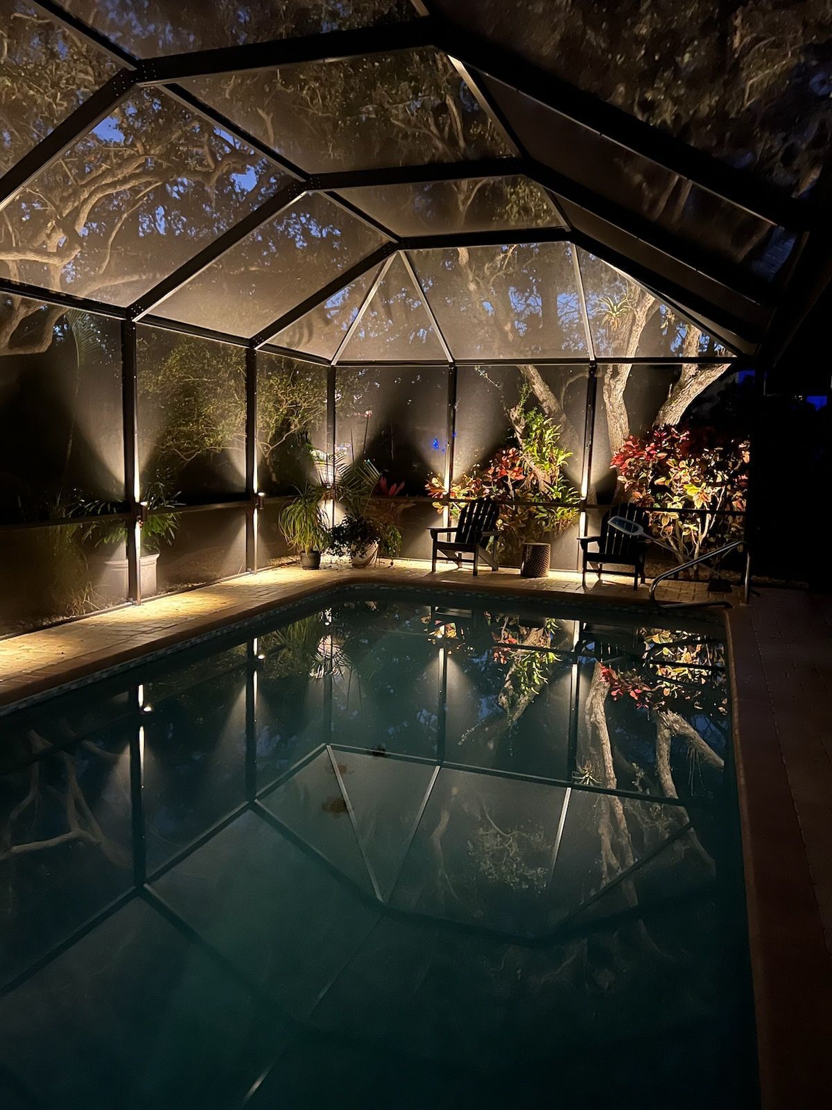 Indoor pool with dark walls, a geometric roof, and accent lighting.