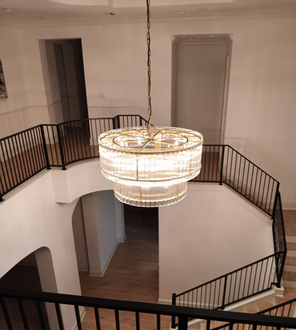 Grand staircase with black railings, white walls, and a large chandelier.