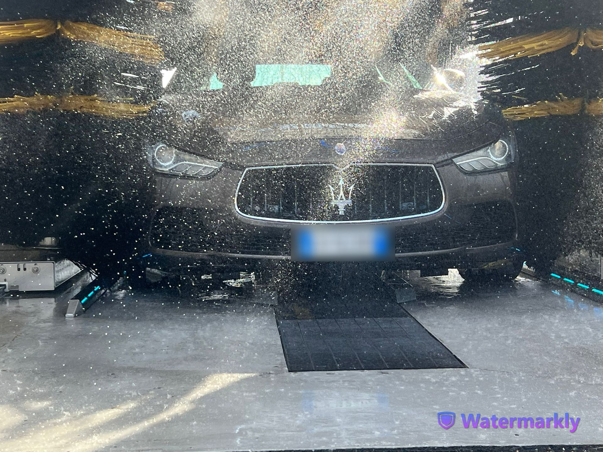 A car is being washed in a watermarkly car wash