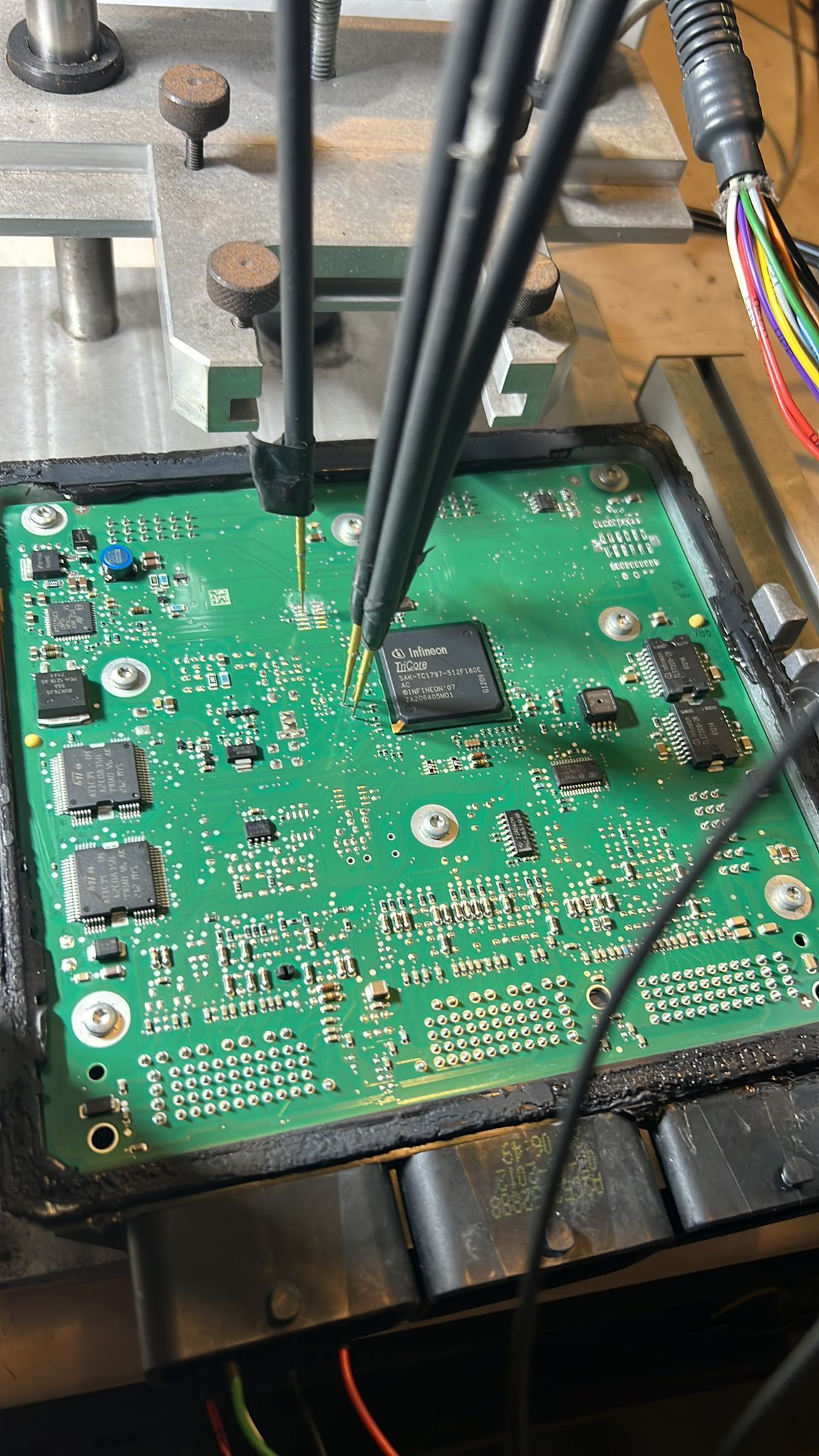 A green motherboard is being worked on with a pair of tweezers.