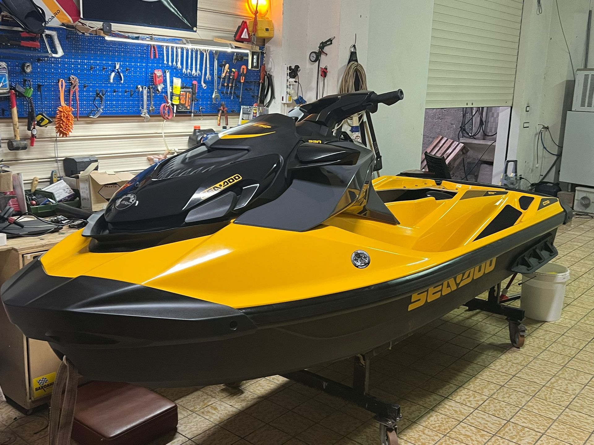 A yellow and black jet ski is parked in a garage.