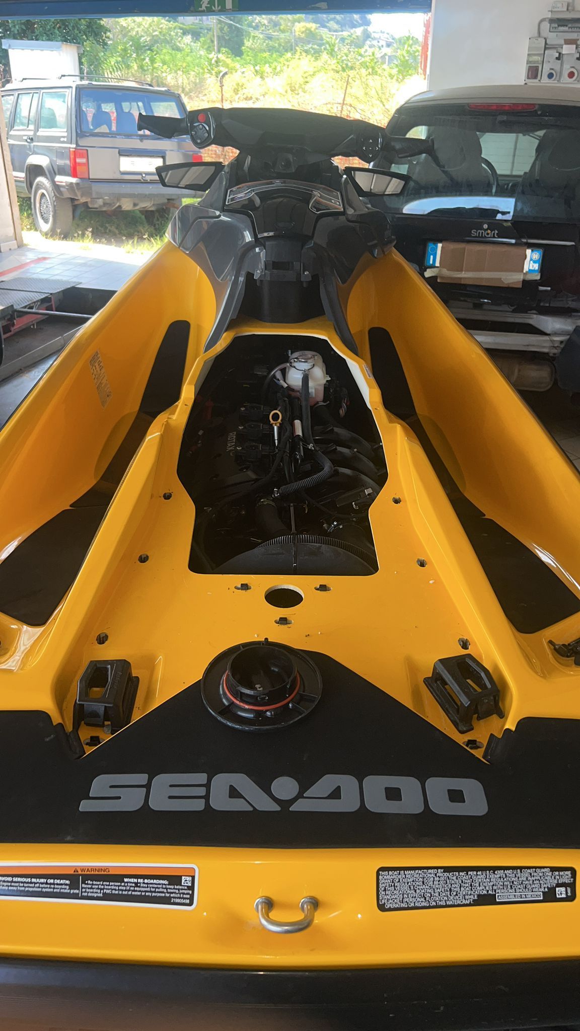 A yellow sea doo jet ski is parked in a garage.