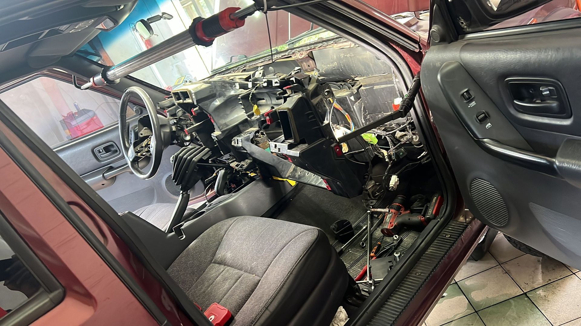 The inside of a car with the door open and the dashboard removed.