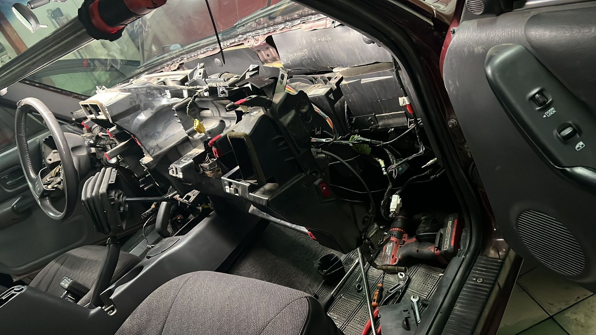 The inside of a car with the door open and the dashboard removed.