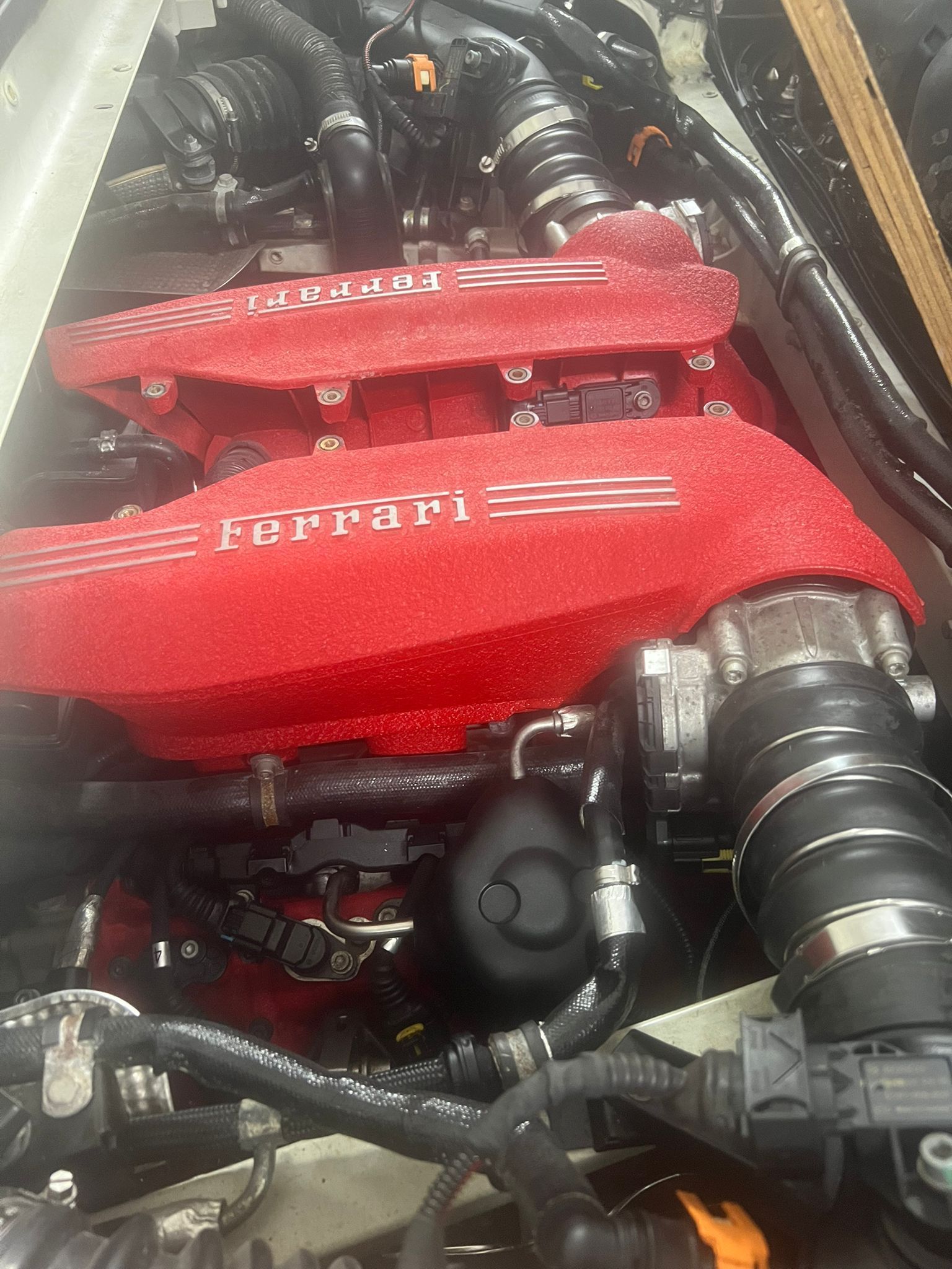 A close up of a ferrari engine with a red cover on it.