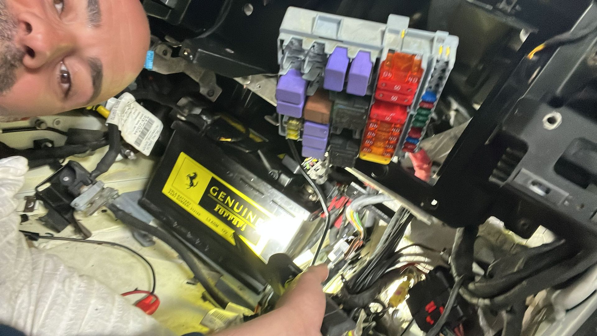 A man is working on a car with a genuine ferrari battery