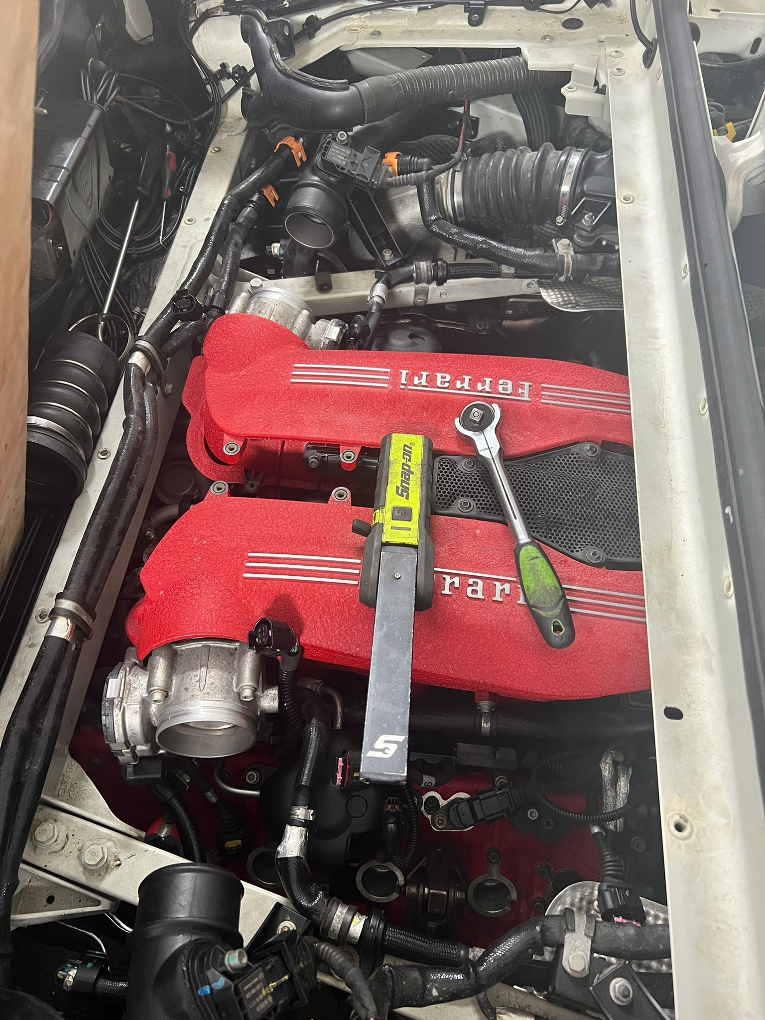 A close up of a car engine with a wrench on it.