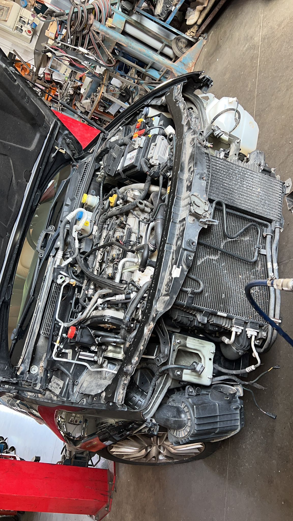 The engine of a car is sitting on top of a pile of scrap metal.