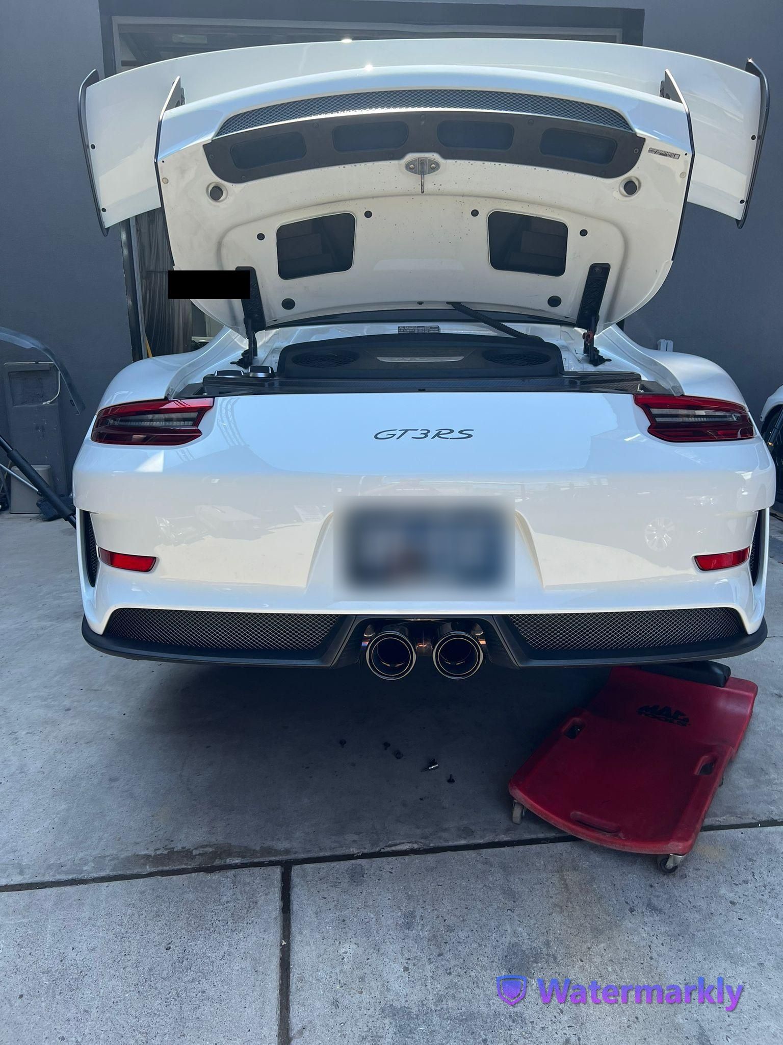 A white sports car with the hood up is parked on the side of the road.