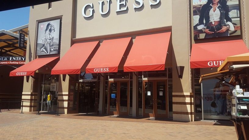 A guess store with red awnings on the front of it