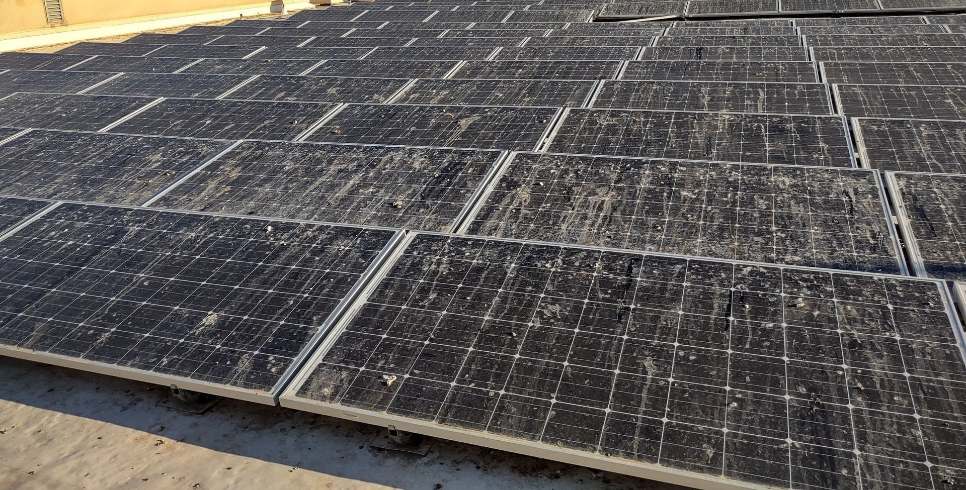 a row of dirty solar panels on a roof