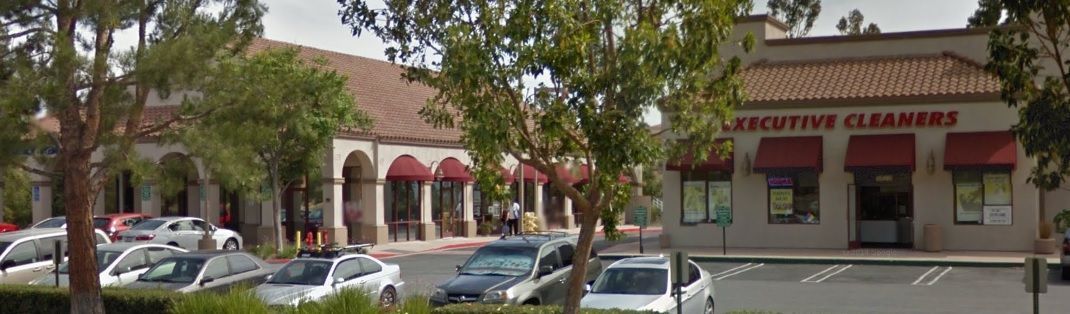 A building with a lot of cars parked in front of it and red awnings.