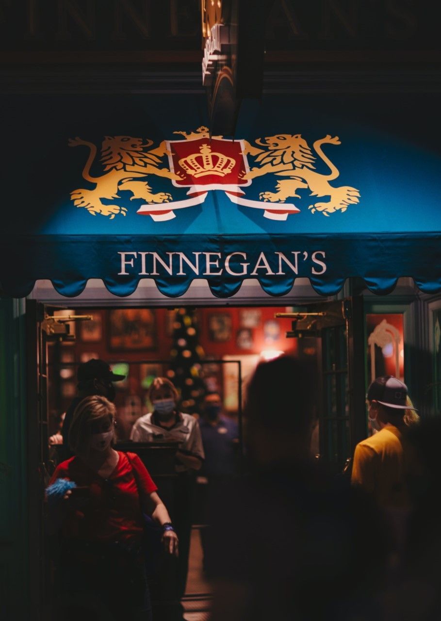 A group of people are walking in front of a restaurant with a fancy blue awning