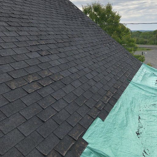 The roof of a house is covered with a green tarp.